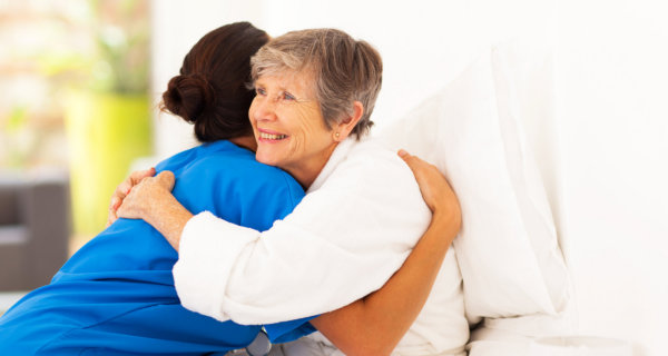 caregiver and elderly woman hugging