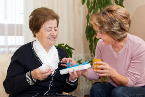 caregiver giving elderly woman her medicine