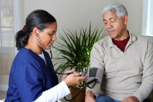 caregiver monitoring elderly man's blood pressure